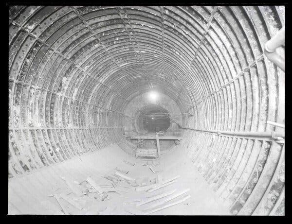 A faded black-and-white photograph of an empty tunnel under construction.